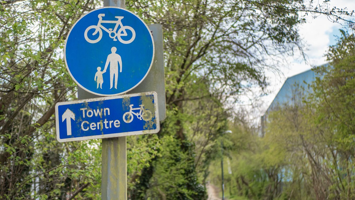 Shared use path blue roundel sign with a rectangular, blue wayfinding sign marked "Town Centre" with a bike logo.