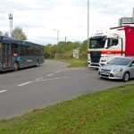 Longford Road meets the roundabout. A car waits to join in the left lane, a lorry waits in the right lane, and a bus passes on the roundabout.